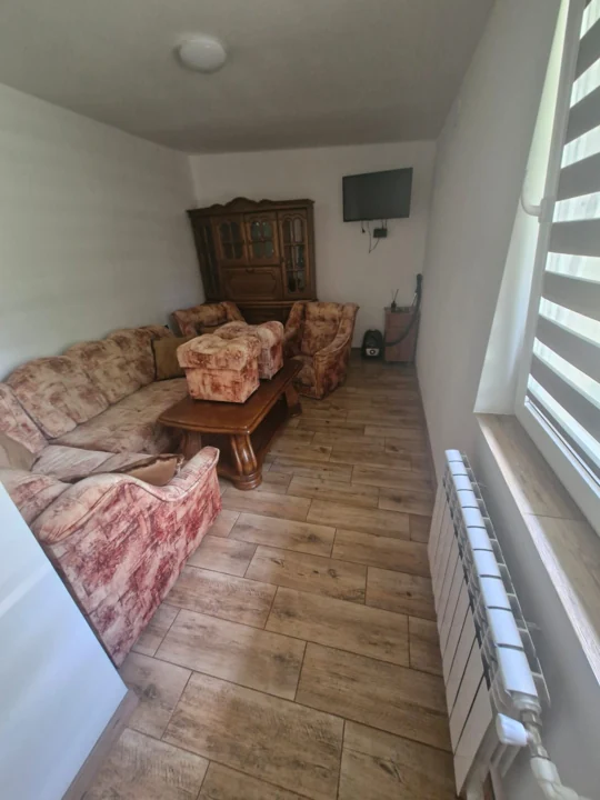 Salon z wzorzystą sofą, fotelami i drewnianymi meblami